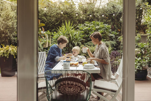 Two happy mothers at breakfast table outdoors with their child - MFF04417