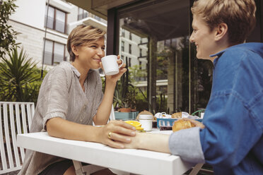 Zwei glückliche Frauen am Frühstückstisch auf ihrer Terrasse - MFF04419