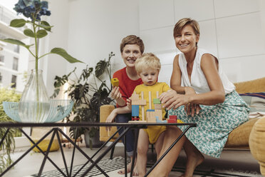 Portrait of two mothers learning and playing with their child at home - MFF04431