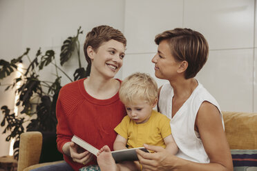 Zwei Mütter lesen mit ihrem Kind zu Hause ein Buch - MFF04434