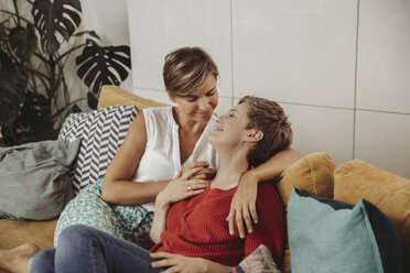 Glückliches lesbisches Paar kuschelnd auf Couch - MFF04437