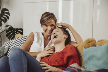 Happy lesbian couple laughing and cuddling on couch - MFF04438