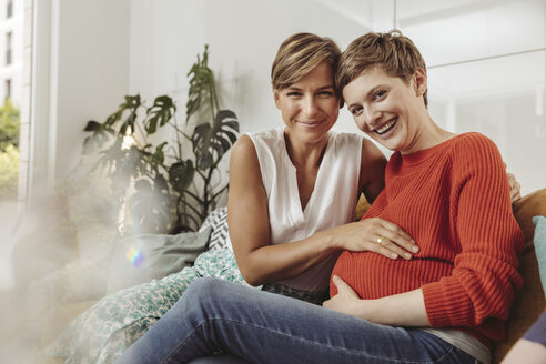 Porträt eines glücklichen lesbischen Paares, das den Bauch der werdenden Mutter berührt - MFF04441