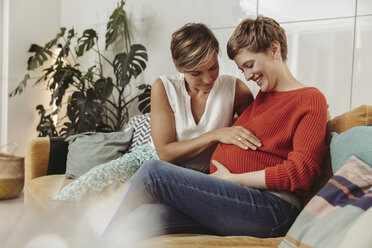 Glückliches lesbisches Paar berührt den Bauch der werdenden Mutter - MFF04442