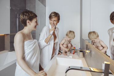 Lesbisches Paar und ihr kleiner Sohn machen sich im Badezimmer für den Tag bereit - MFF04449