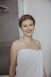 Porträt einer glücklichen Frau, eingewickelt in ein Handtuch, im Badezimmer - MFF04450