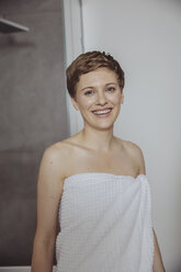 Portrait of happy women wrapped in towel standing in bathroom - MFF04450