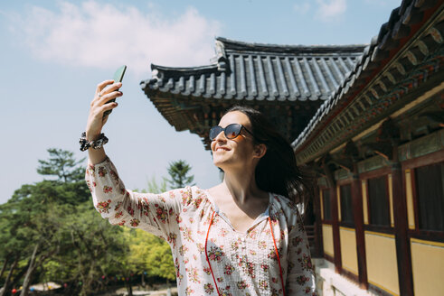 Südkorea, Gyeongju, glückliche Frau macht ein Selfie mit Handy im Bulguksa-Tempel - GEMF02397