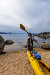 Man with a paddle over his shoulder dragging a kayak. - AURF03405