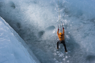 Mann klettert vertikale Gletschereiswand - AURF03406