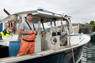 Porträt eines stolzen Hummerfischers, der auf seinem angedockten Boot steht - AURF03469