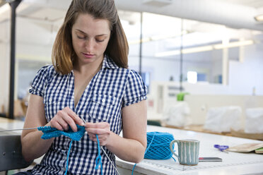 Portrait of female artist knitting in fiber arts studio - AURF03471