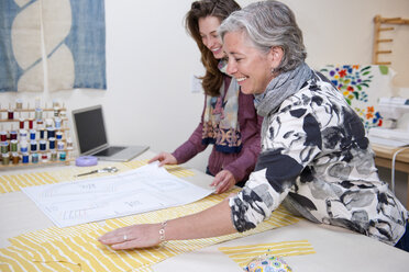 Senior-Bekleidungsdesignerin und Kleinunternehmerin bespricht Pläne mit Mitarbeiterin im Atelier für Faserkunst - AURF03512