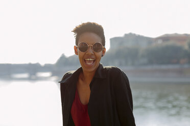 Italien, Verona, Porträt einer lachenden jungen Frau mit Sonnenbrille - GIOF04263