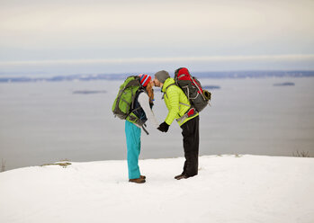 Ein Paar küsst sich im Winter auf dem Gipfel eines Berges an der Küste von Maine. - AURF03551