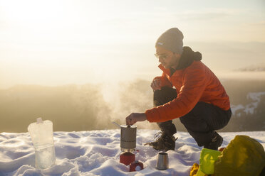 Ein Bergsteiger kümmert sich beim Zelten in den Bergen um seinen Kocher. - AURF03601