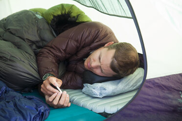 A climber checks his e-mail from his tent while camping in the mountains. - AURF03603