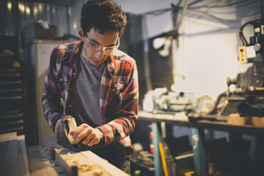 A carpenter works on a piece of wood with a hand planer. - AURF03618