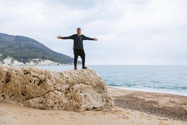 Italy, Vieste, relaxed man with arms outstretched standing on a rock on Vignanotica Beach - FLMF00006