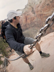 Ein Wanderer hält sich an einer Kette fest, um sich beim Wandern auf dem Angel's Landing Trail im Zion National Park zu stützen - AURF03639