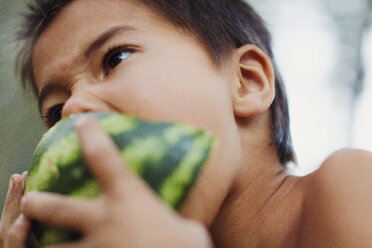 A little boy with bare upper body eats a watermelon. - AURF03648