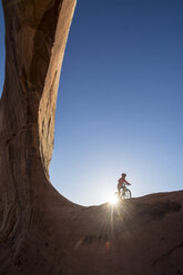 Ein Mädchen fährt mit dem Mountainbike am Wilson Arch in der Nähe von Moab, Utah. - AURF03659