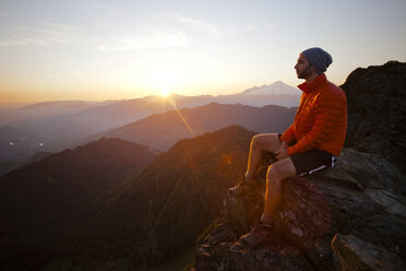 Ein Wanderer beobachtet den Sonnenuntergang von einer Felswand auf dem Gipfel des Sauk Mountain. - AURF03693
