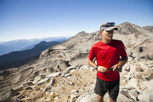 Ein Wanderer benutzt sein Smartphone, um Fotos vom Gipfel des Cassiope Peak in der Nähe von Pemberton, British Columbia, Kanada, aufzunehmen. - AURF03694
