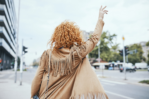 Redheaded woman hailing a taxi in the street stock photo