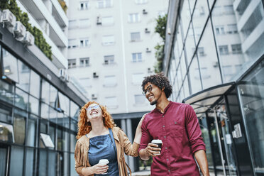 Colleagues walking together in the city, woman drinking coffee - ZEDF01520