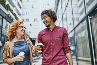 Colleagues walking together in the city, woman drinking coffee - ZEDF01521