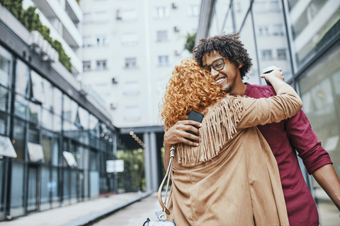 Colleagues meeting in the city, embracing stock photo