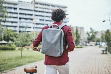 Junger Mann mit Rucksack schiebt Fahrrad im Park - ZEDF01537