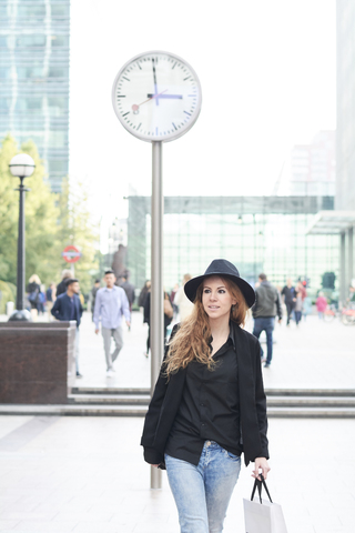 Mittlere erwachsene Frau mit Hut beim Einkaufen in der Stadt, lizenzfreies Stockfoto