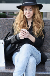 Mid adult woman wearing black hat and using smartphone - IGGF00562