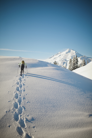Ein Schneeschuhwanderer geht über einen verschneiten Bergrücken., lizenzfreies Stockfoto