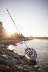 A small sailboat smashed up on the rocky shoreline of Sunset Beach, Vancouver. - AURF03747