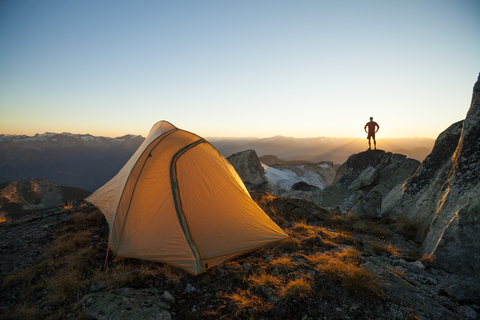 Ein Wanderer mit Silhouette steht auf einer Felswand beim Zelten auf dem Saxifrage Peak, Pemberton, BC, Kanada., lizenzfreies Stockfoto