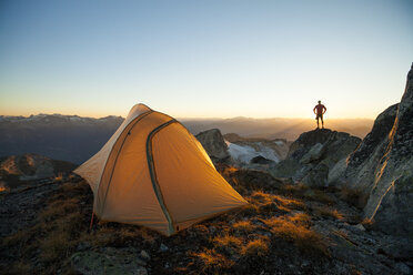 Ein Wanderer mit Silhouette steht auf einer Felswand beim Zelten auf dem Saxifrage Peak, Pemberton, BC, Kanada. - AURF03748