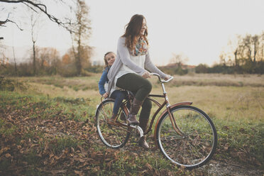 A mother pedals an old fashioned bike while her daught rides on the back. - AURF03751