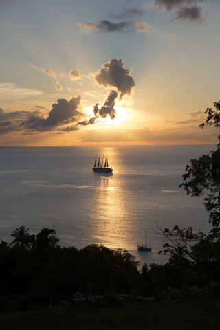 Ein Segelboot kreuzt durch einen Sonnenuntergang, lizenzfreies Stockfoto