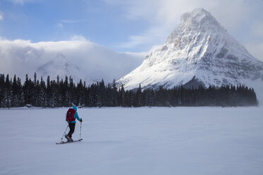 A woman skiing on Two Medicine Lake in front of Sinopah Mountain and Painted Tepee Peak in Glacier National Park, Montana. - AURF03799