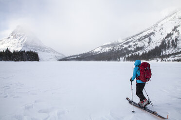 Eine Frau fährt auf dem Two Medicine Lake vor dem Sinopah Mountain im Glacier National Park, Montana, Ski. - AURF03800