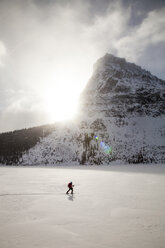 Eine Frau fährt auf dem Two Medicine Lake vor dem Sinopah Mountain im Glacier National Park, Montana, Ski. - AURF03801