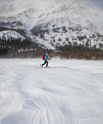 A woman skis on wind patterned snow at Two Medicine Lake, Glacier National Park, Montana. - AURF03802