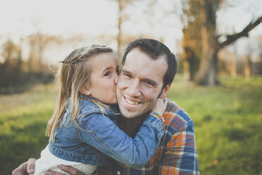 A young girl kisses her dad on the cheek. - AURF03827