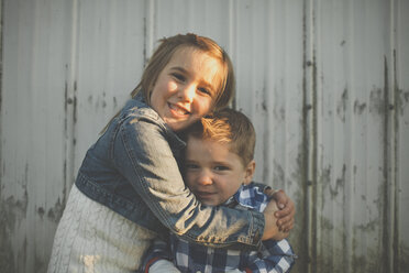 Ein junges Mädchen umarmt ihren jüngeren Bruder. - AURF03828