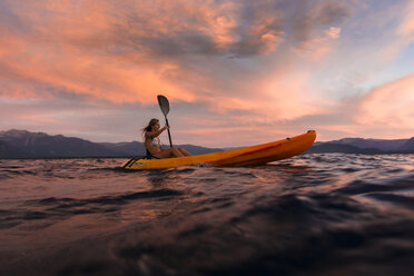 Eine Frau paddelt bei Sonnenuntergang auf dem Lake Tahoe in einem Kajak. - AURF03839