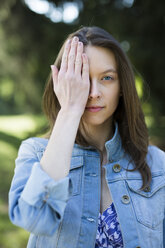 Porträt einer jungen Frau im Freien, die ein Auge bedeckt - GIOF04278