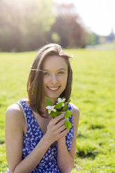 Porträt einer lächelnden jungen Frau in einem Park mit Blumen - GIOF04280